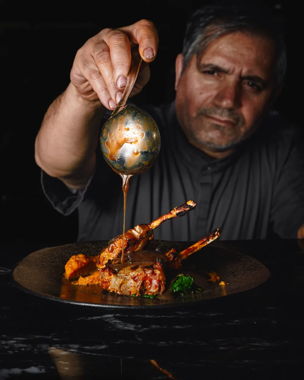The chef finishing a dish in the kitchen