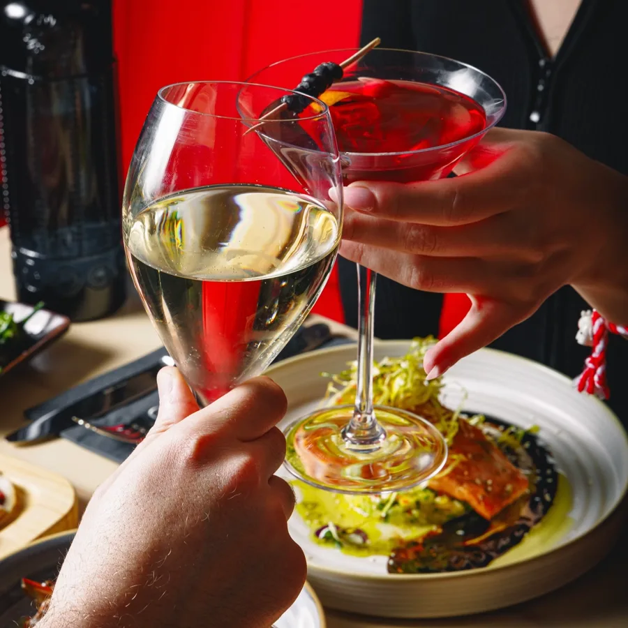 Two cocktails being raised over a table of tapas