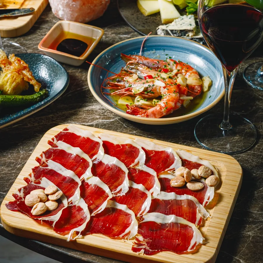 A platter of thinly sliced Ib&eacute;rico ham with almonds