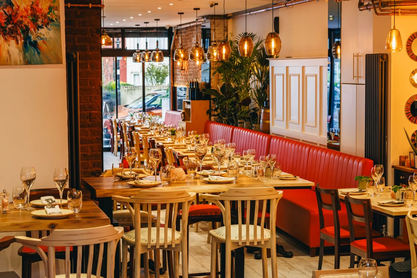 The dining room, with brick walls, brass pendant lights and red banquettes